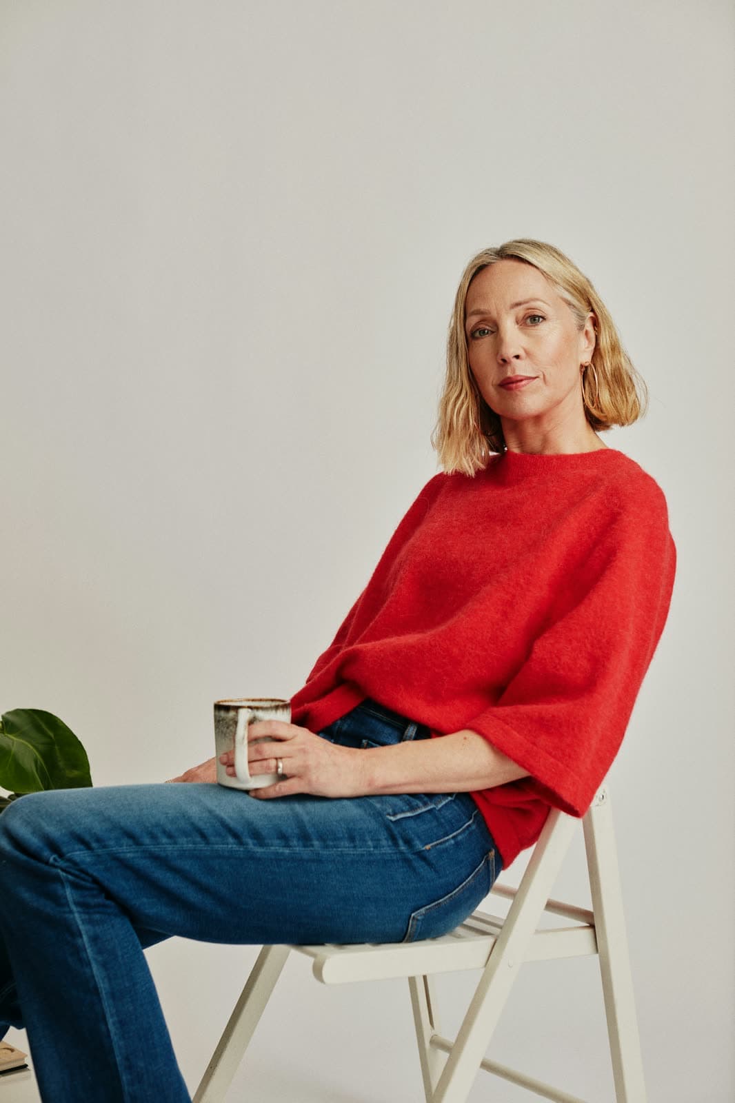 A woman in a red jumper sitting with a cup of tea
